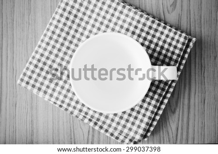 empty coffee cup on brown kitchen towel and wood table black and white color tone style