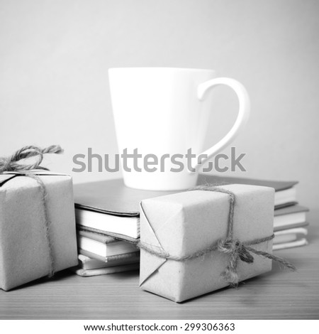 book with gift box and coffee mug on wood background black and white tone style