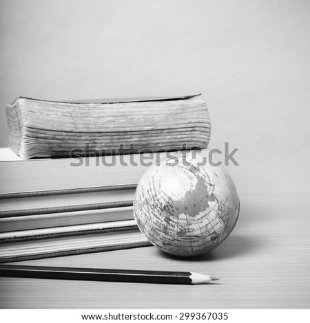 book and earth ball with black pencil on wood background black and white color tone style
