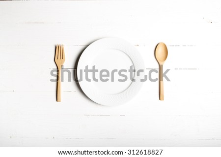 wood spoon and fork with dish over white table background