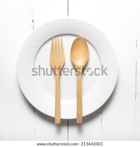 wood spoon and fork with dish over white table background