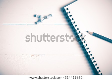 pencil and notepad with push pin over white table view from above vintage style