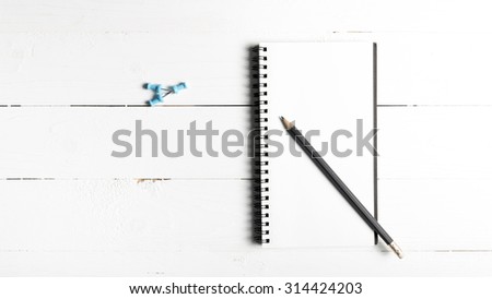pencil and notepad with push pin over white table view from above