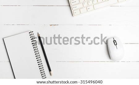notepad and computer on white table background view from above