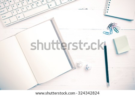 computer and notebook with office supplies over white table vintage style