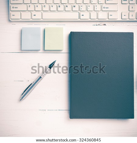 computer and brown notebook with office supplies on white table vintage style