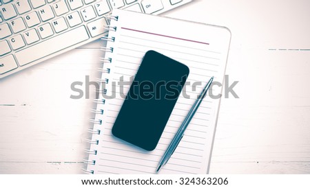 computer and notepad with smart phone over white table vintage style