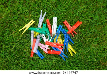 Pile of clothes pegs of different colors on blades of grass