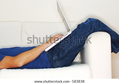 Profile shot of casual guy lying down working on laptop (high key)