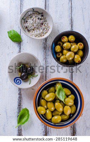 Assortment of olives with herb and sea salt on white wooden back
