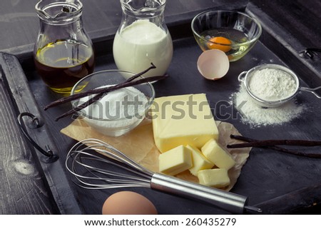 Baking ingredients eggs, flour, sugar, butter, vanilla, cream on a tray