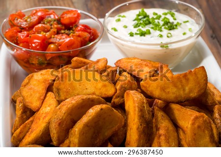 Potato wedges with dip and roasted tomatoes and fresh chives