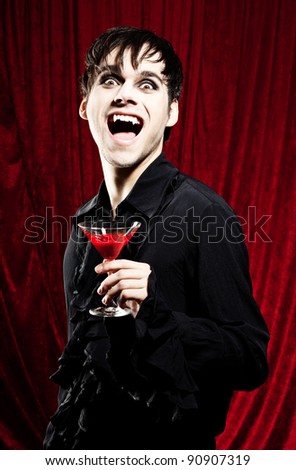 Male vampire with a glass of red blood in his hands, looking dangerous