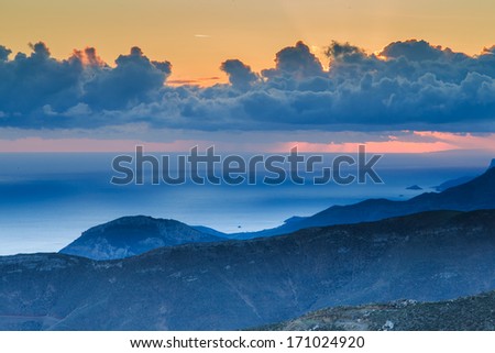 Beautiful ethereal mountain sunset at twilight with atmospheric blue lighting on the peaks and a towering formation of cumulus cloud in the orange sky