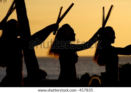 Luau dancers against a sunset sky on Oahu.