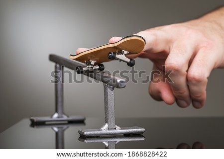 A man plays with a fingerboard on a gray metal railing. Stock foto © 