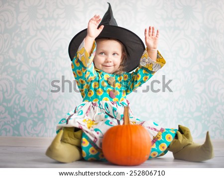 Little witch in black hat with pumpkin