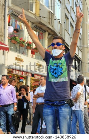 ISTANBUL - JUN 17: Labor unions call 1-day nationwide strike over crackdown on June 17, 2013 in Istanbul, Turkey. A protester makes victory sign in front of riot police during protest at Istiklal St.