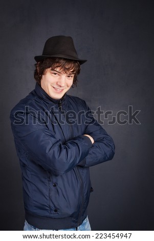 Young man with black hat on gray background expressing positivity..