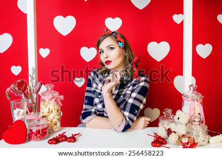 Beautiful young woman in pin-up style on red with white hearts background