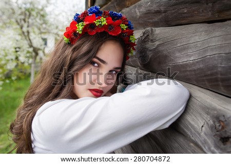 young beautiful girl with long dark hair in Ukrainian blouse and in a wreath in outdoor ethnic village Pirogovo in Kiev Ukraine