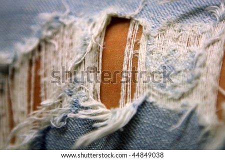 Close-up of woman\'s leg in torn blue jeans