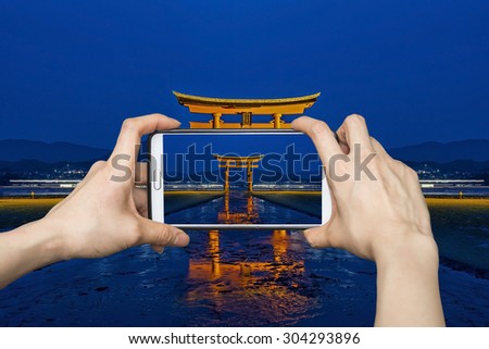 Girl taking pictures on mobile smart phone in Tori gate,Hiroshima,Japan