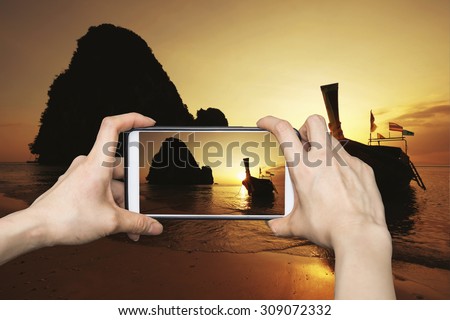 Girl taking pictures on mobile smart phone in Sunset summer landscape in the mountain and sea , Krabi , Thailand