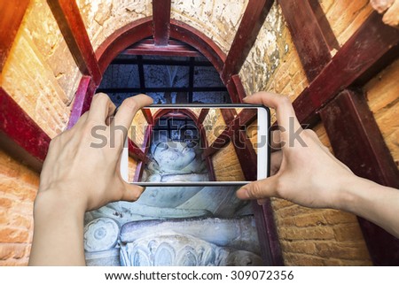 Girl taking pictures on mobile smart phone Buddha in Bagan, Myanmar