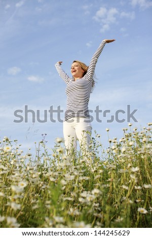 Happy woman with stretched arms in flower field
