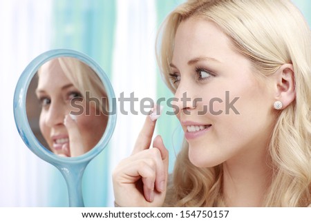 Attractive woman applies cream on her face