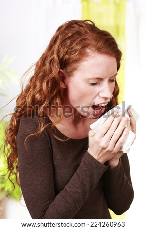 Woman sneezes with handkerchief