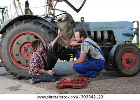teamwork:Father and son repairing a tractor outdoor