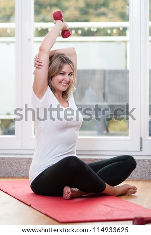 Attractive young woman makes fitness training with dumb bells