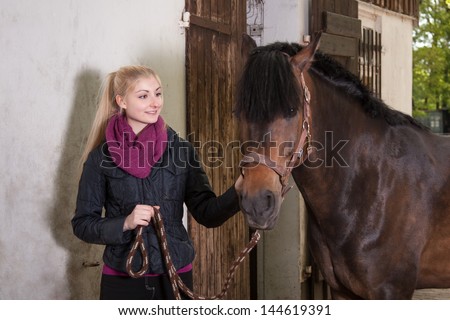 Girl is holding brown pony (New-Forest-Pony) on a leash