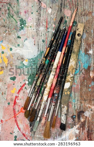 paint brushes on grungy paint splatter wood background