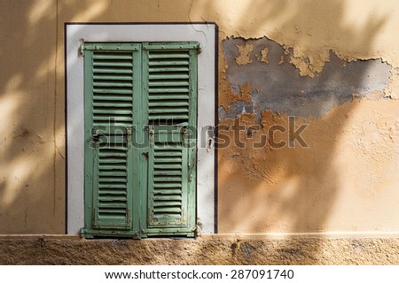 french window shutters on grungy wall with tree shadows