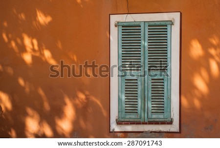 green french window shutters on orange wall tree shadows