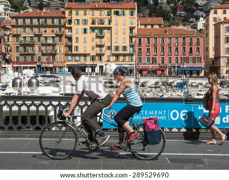 Nice, France - 13th may 2015: Tourists sightseeing on tandem bicycle cycling by the port of Nice on a  sunny may afternoon
