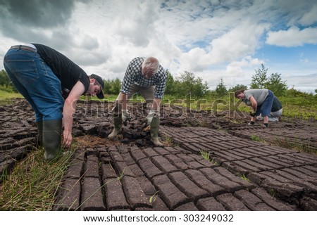 County Kerry, Ireland - May 31, 2014: Workers cultivating a peak bog field outside the town of Listowel in County Kerry