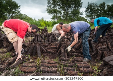 County Kerry, Ireland - June 14, 2014: Workers cultivating a peak bog field outside the town of Listowel in County Kerry
