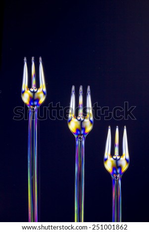 Isolated transparent polarized forks on a lighting technique on a black background.