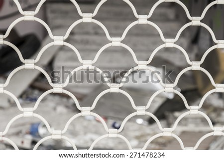 Detail of an old white metal blind fence on a shop