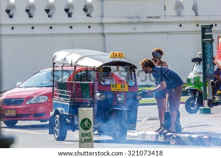 BANGKOK, THAILAND - SEPTEMBER 26, 2015 : Tourist ask Tuk-Tuk driver how to pay. Samlors or three wheeled bikes should not be missed for tourists in Bangkok.