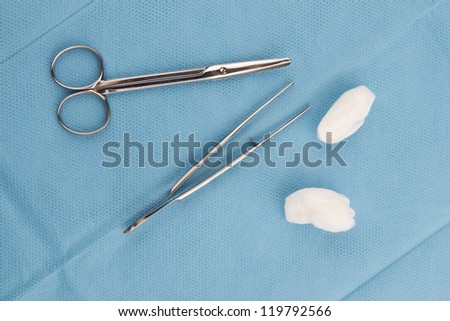 Medical scissors, tweezers and swabs close up on blue background