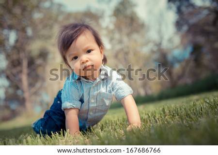 Cute one year old boy playing outside in a grassy suburban park