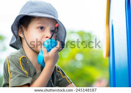 Cute 4 year old mixed race Asian Caucasian boy plays outside in a playground with a toy walkie talkie radio