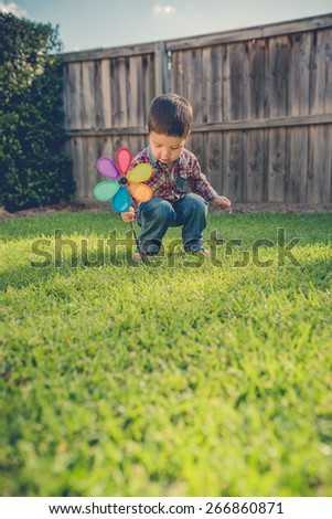 Cute 2 year old mixed race Asian Caucasian boy plays with a garden ornament in the backyard of his suburban home. Filtered effects