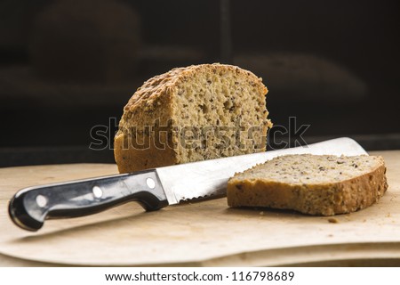 bread sliced/ a loaf of fresh organic wholemeal bread being sliced on a wooden chopping board