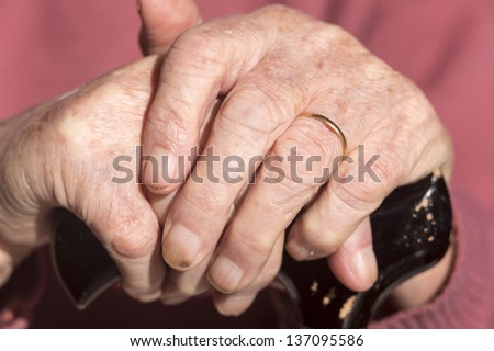 Elderly Woman\'s Hands/ an elderly widow rests her hands on her walking cane
